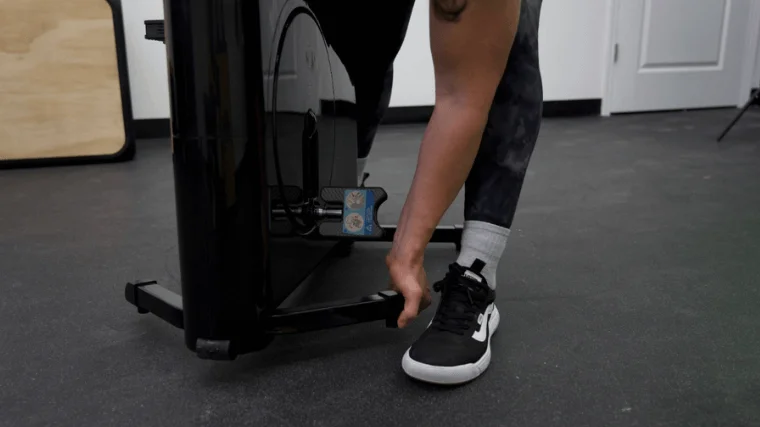 Our tester unlocking and setting the stabilizer legs of the Sharper Image Space Saving Stationary Bike