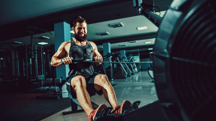 A fit muscular person working out in the gym on a rowing machine.