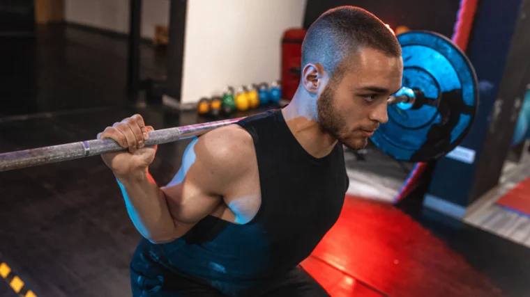 A fit person lifting a barbell in the gym.