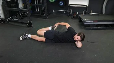 BarBend's Jake Herod performing the lying quad stretch.