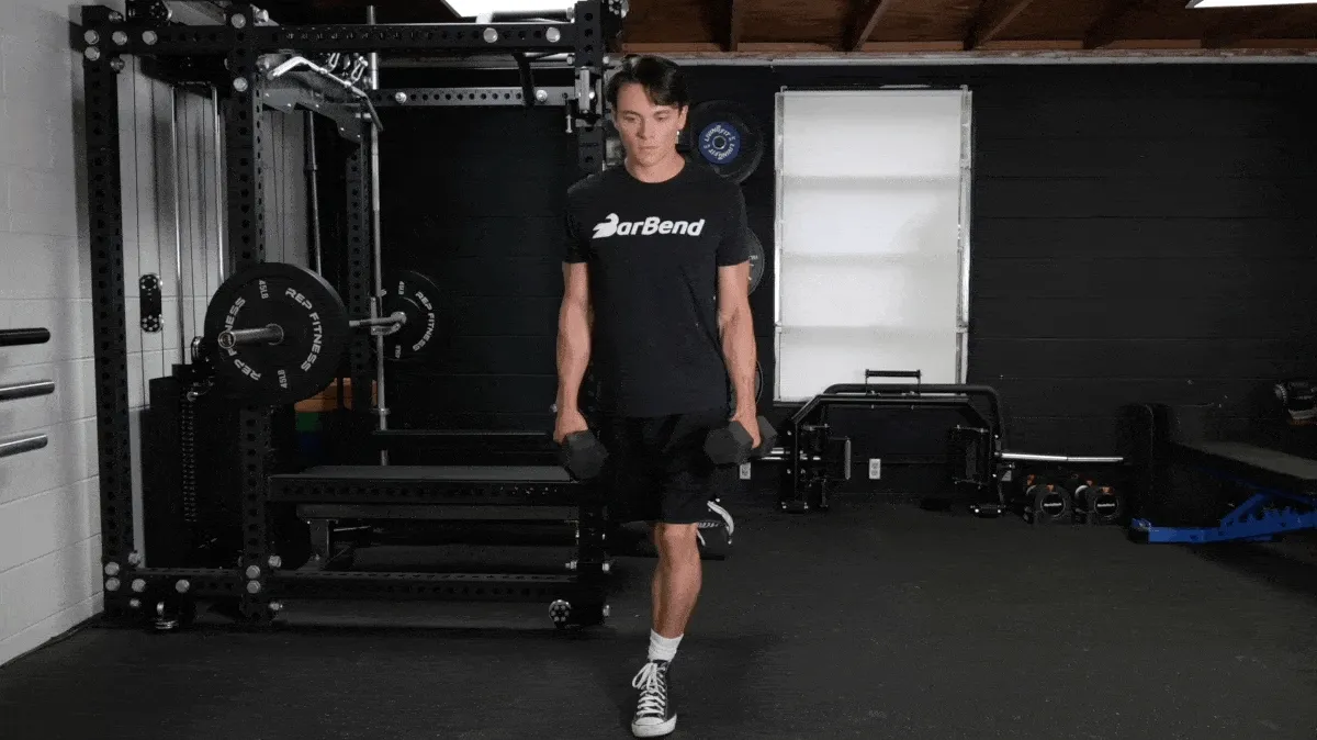 Jake performing the modified curtsy lunge exercise in the BarBend gym.
