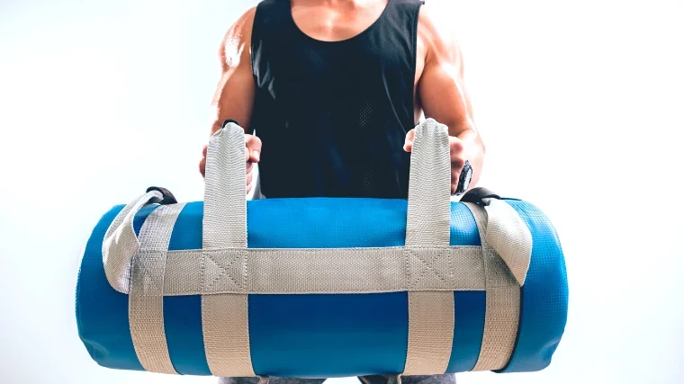Athlete training with a sandbag in the gym.