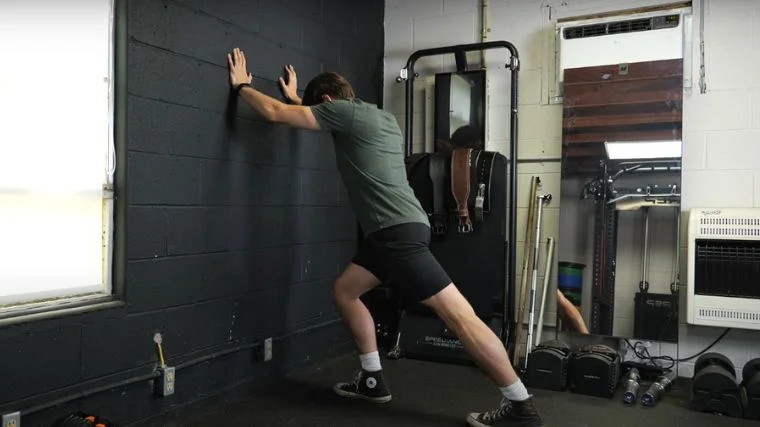 BarBend's Jake Herod doing the wall calf stretch.