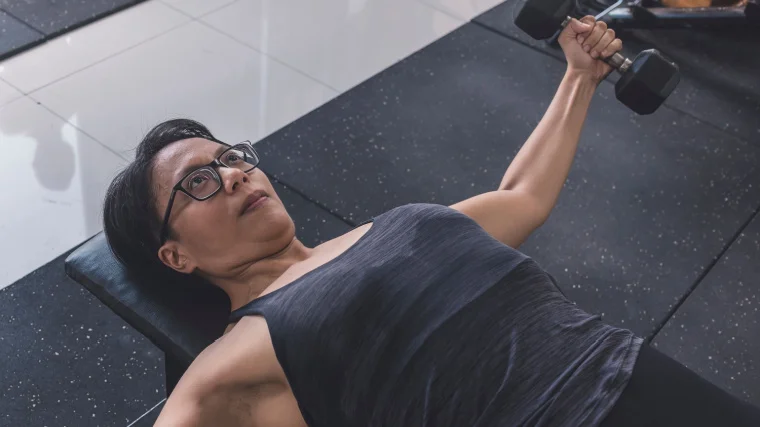 An athlete wears glasses while performing dumbbell flyes.