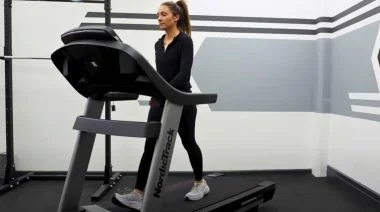 A BarBend tester walking on a treadmill in the gym.