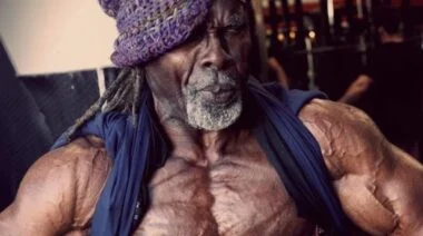 A photo of bodybuilder Robby Robinson wearing a knit cap and vest flexing his abs.