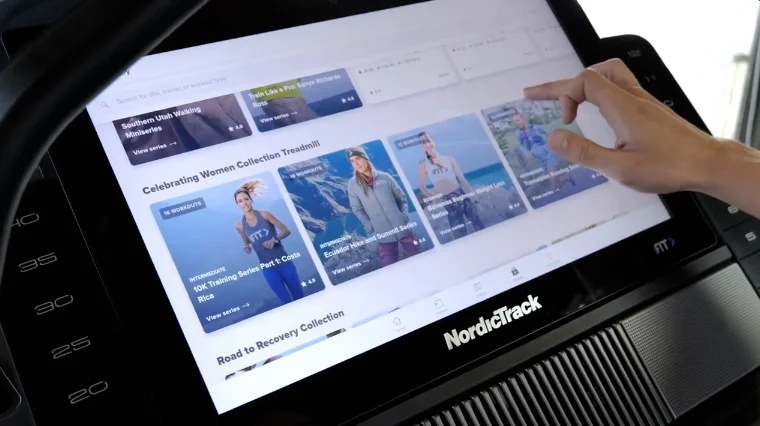 A hand can be seen browsing iFit on the NordicTrack Commercial X22i.