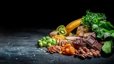 Assortments of foods high in magnesium like bananas, nuts, oatmeal, buckwheat, peanuts, spinach chard, dark chocolate, sesame seeds and more.