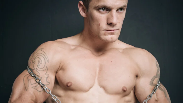 A shirtless muscular person with acne.