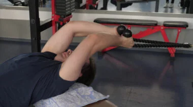 A person performs a cable pullover in the gym.