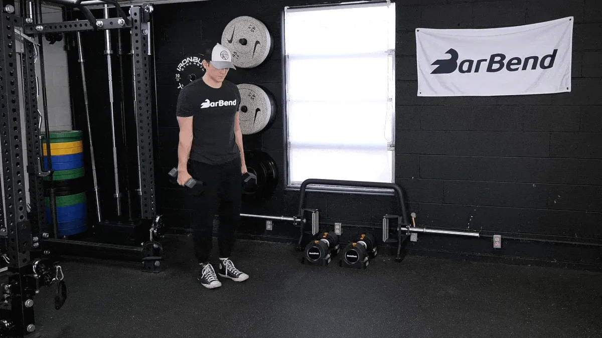 A person performing the dumbbell lunge movement in the gym.
