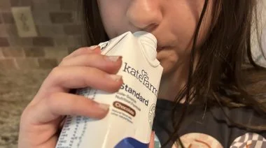 A kid drinks a shake made from one of the best protein powders for kids.