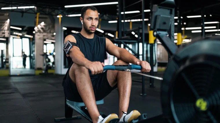 A person works out on a rowing machine in the gym.