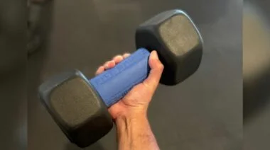 A hand holding a dummbell with a fat gripz attached.