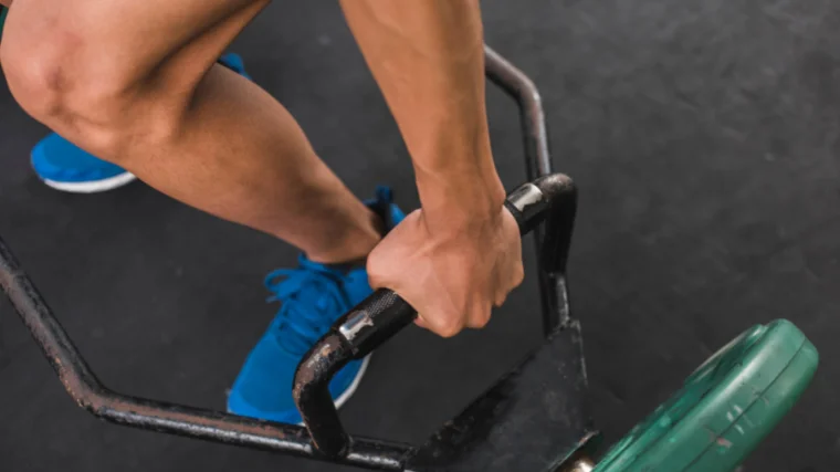 lifter adjusts grip on trap bar before deadlift
