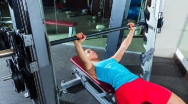 A person bench pressing on a Smith machine.