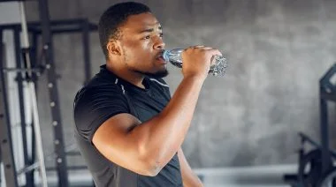 A person in the gym drinking water from a bottle.