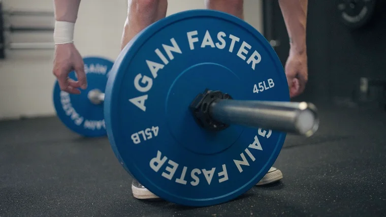 Jake loading the Again Faster Evo Bumper Plates onto a barbell