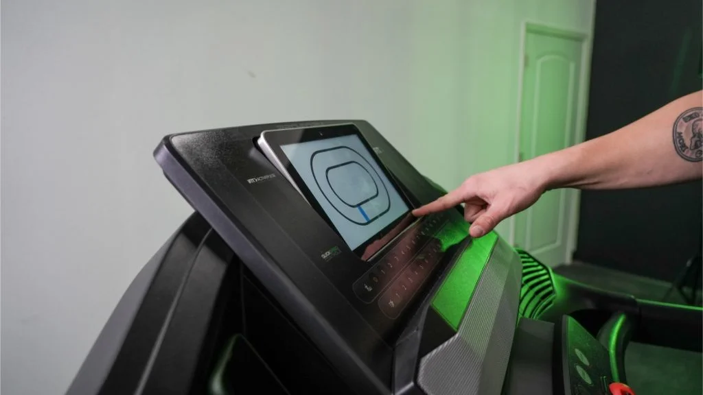 A close up of our BarBend tester adjusting the screen tilt downward on the ProForm Trainer 12.0 treadmill. 