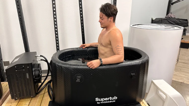 A shirtless person with top surgery scars sitting in the Hydragun Supertub.