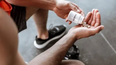 An athlete holding a bottle with probiotic lettering and pills in the gym.