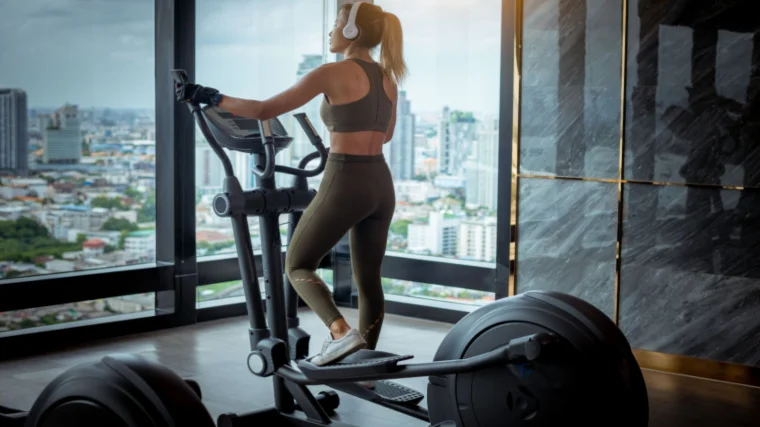 A fit person doing exercise on an elliptical machine in a gym.