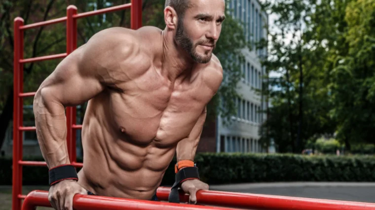 man works chest on parallel dip bars