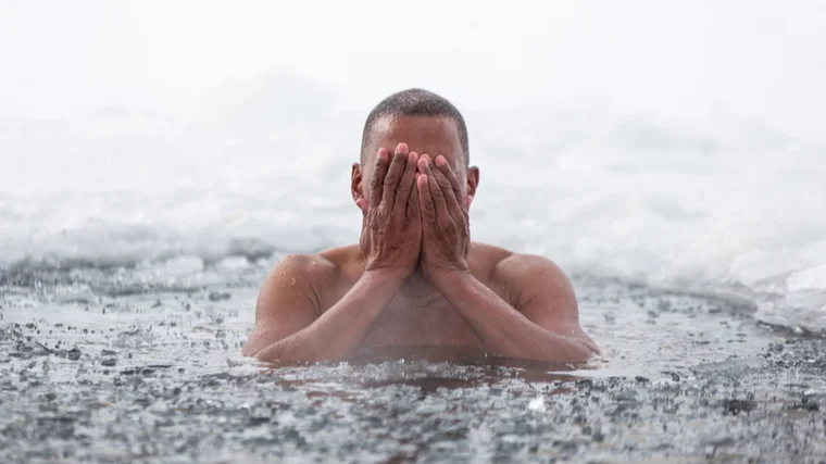 A person emerges from icy water.