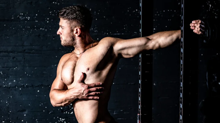 A shirtless athlete stretches their biceps.
