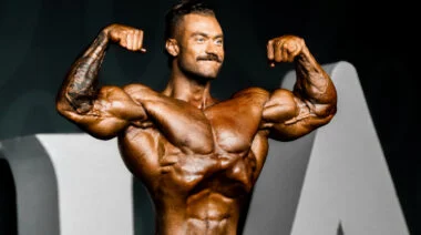 Bodybuilder Chris Bumstead posing on a bodybuilding stage.