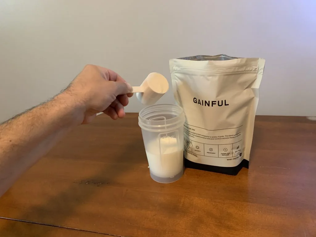 gainful protein powder dumping into cup
