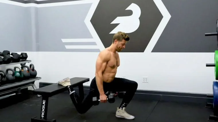 A fitness coach doing the Bulgarian split squat with dumbbells.