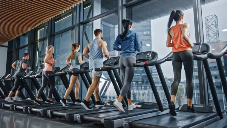 Group of fit people running on a treadmill.