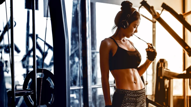 A person turns up their headphones in the gym.