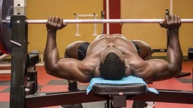 A bodybuilder bench pressing with a barbell.