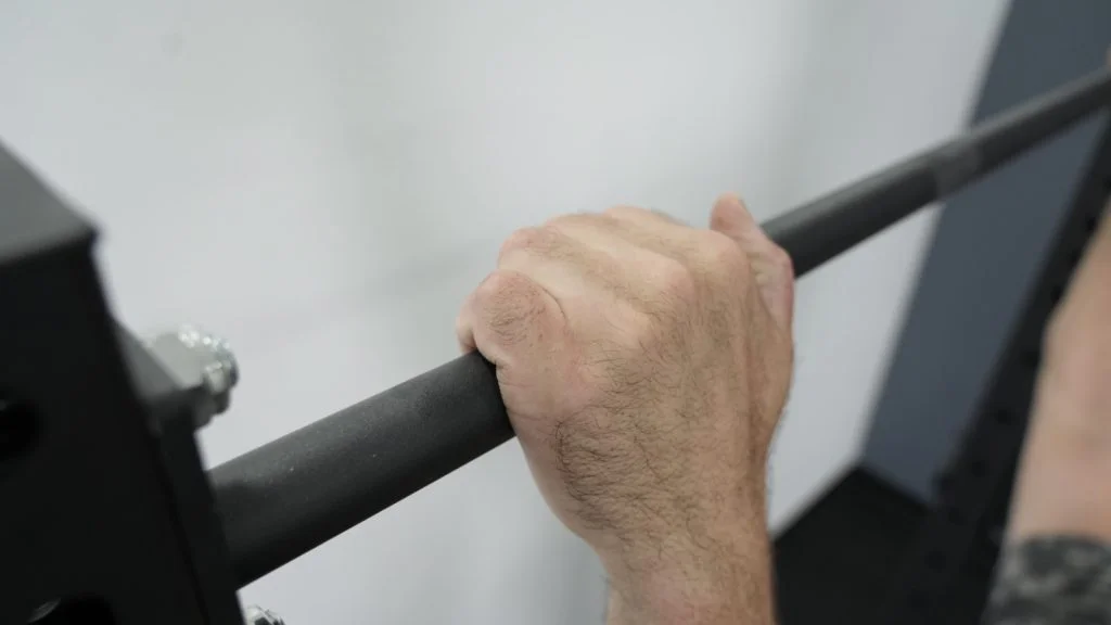 fringe-sport-unlimited-squat-pullup-rack-close-up-hand-on-knurling-of-pull-up-bar A close-up shot of the pull-up bar on the Fringe Sport Unlimited Squat Stand.