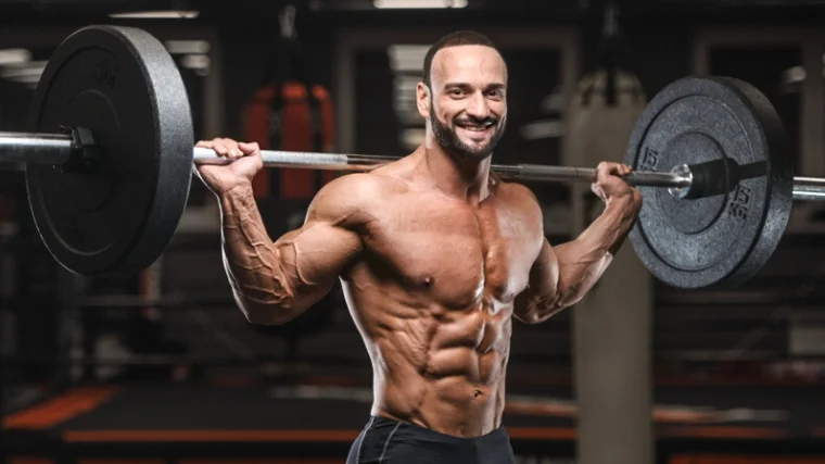 A bodybuilder holding a barbell across his traps.