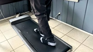 Are walking pads worth it? This image shows a person on a walking pad set partially under a desk.