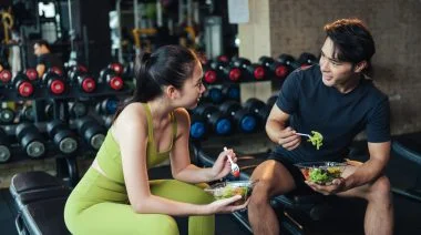 Two people eating salad after working out.