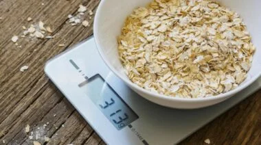 Uncooked oatmeal in a bowl on a scale.