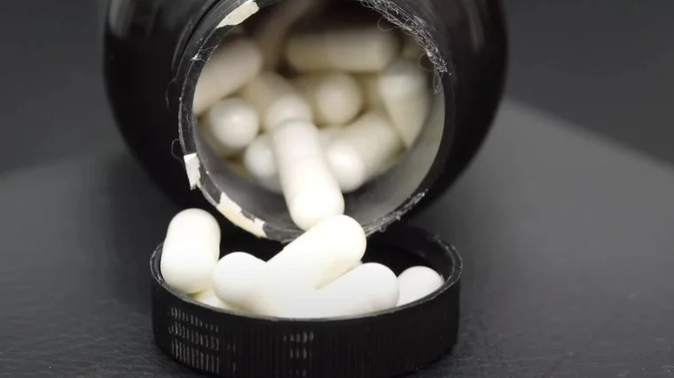 An open bottle of pills poured over the bottle cap.