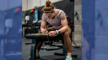 A woman fills out paperwork while straddling a weight bench