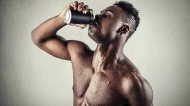 A gymgoer drinking from a can in a gym.