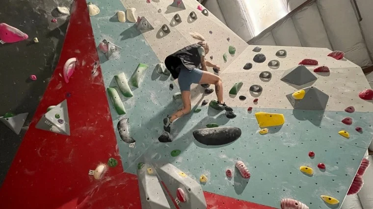 A woman climbing a rock wall with the Columbia Women’s Endless Trail Running Vest.