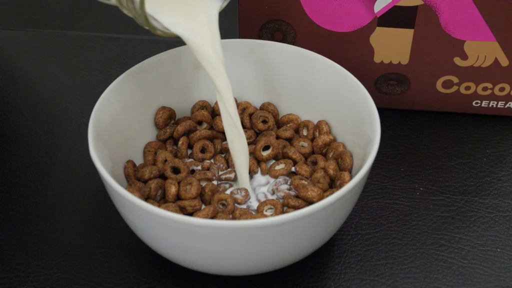 Our tester pours milk over a bowl of Magic Spoon Cereal