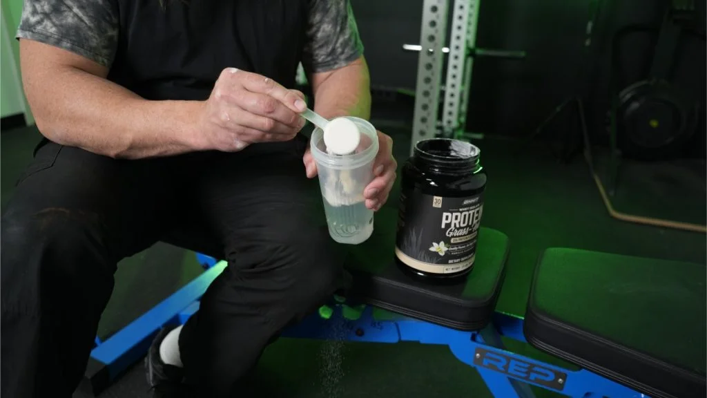 Our tester dumping a scoop of Onnit Whey Protein into a shaker bottle