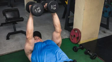 A person presses two dumbbells overhead on a bench with a neutral grip.