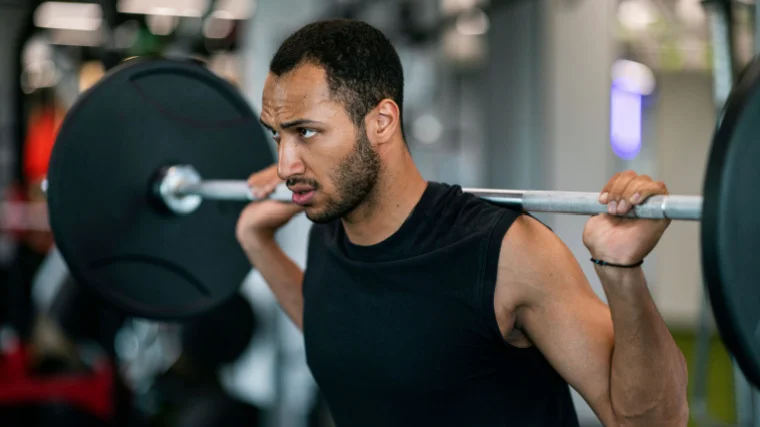 A person prepares to perform a barbell back squat.