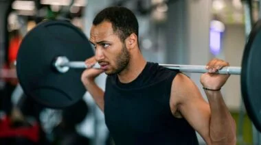 A person prepares to perform a barbell back squat.