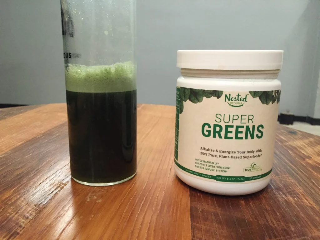 Nested Naturals Super Greens Review A glass and container of Nested Naturals Super Greens Review